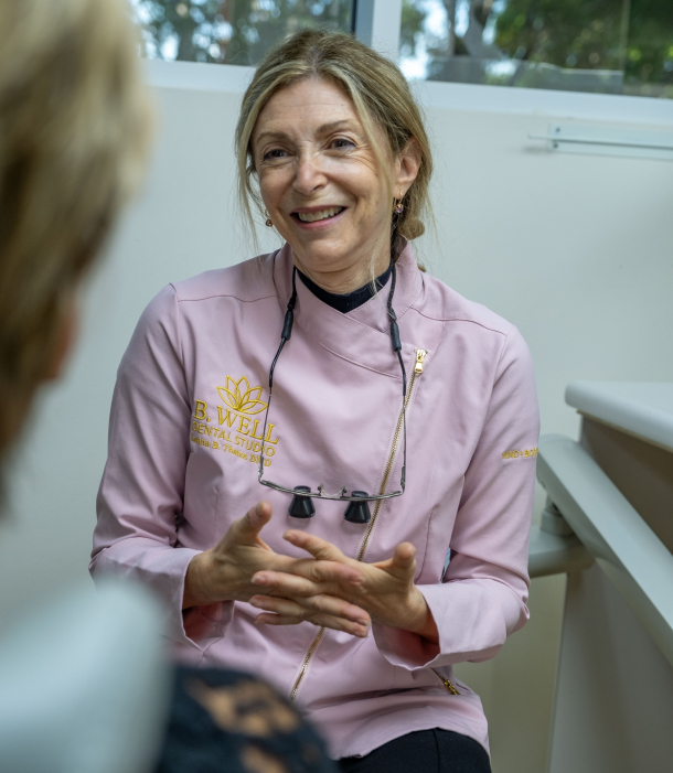 Dr. Leana Thanos smiling while talking with a denture patient in Weston, FL