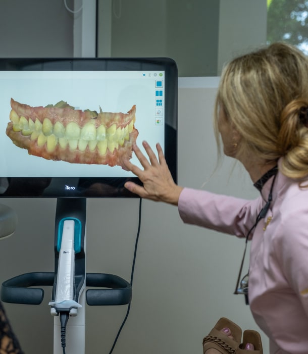 A photo of doctor while showing jaw model on the screen